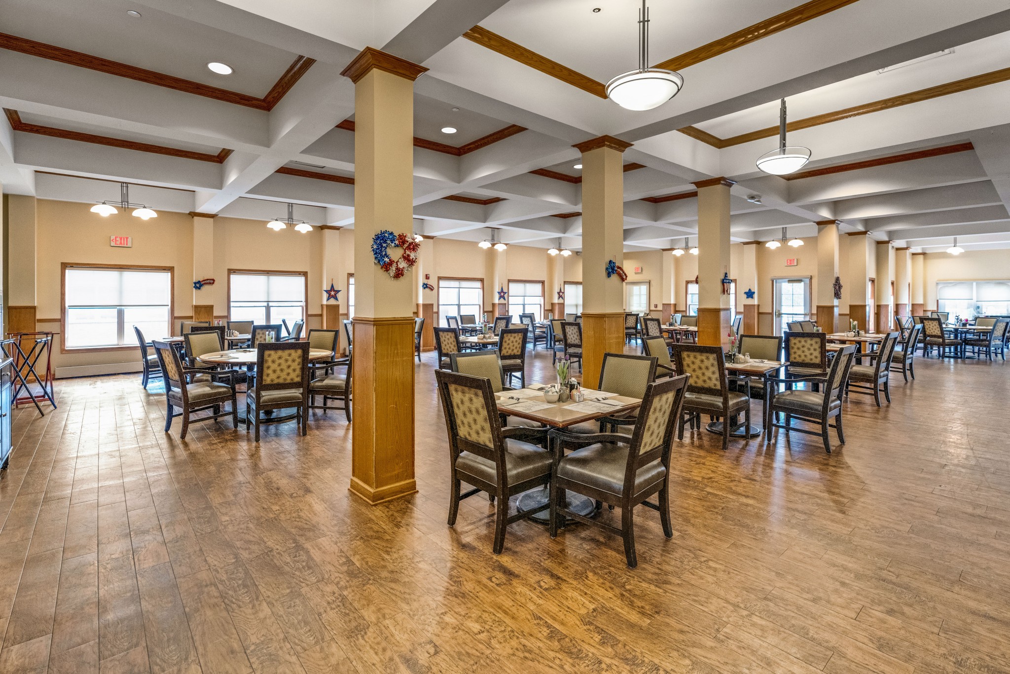 A dining room with square made-up tables and chairs at Town Village Sterling Heights, a senior living community near Detroit.