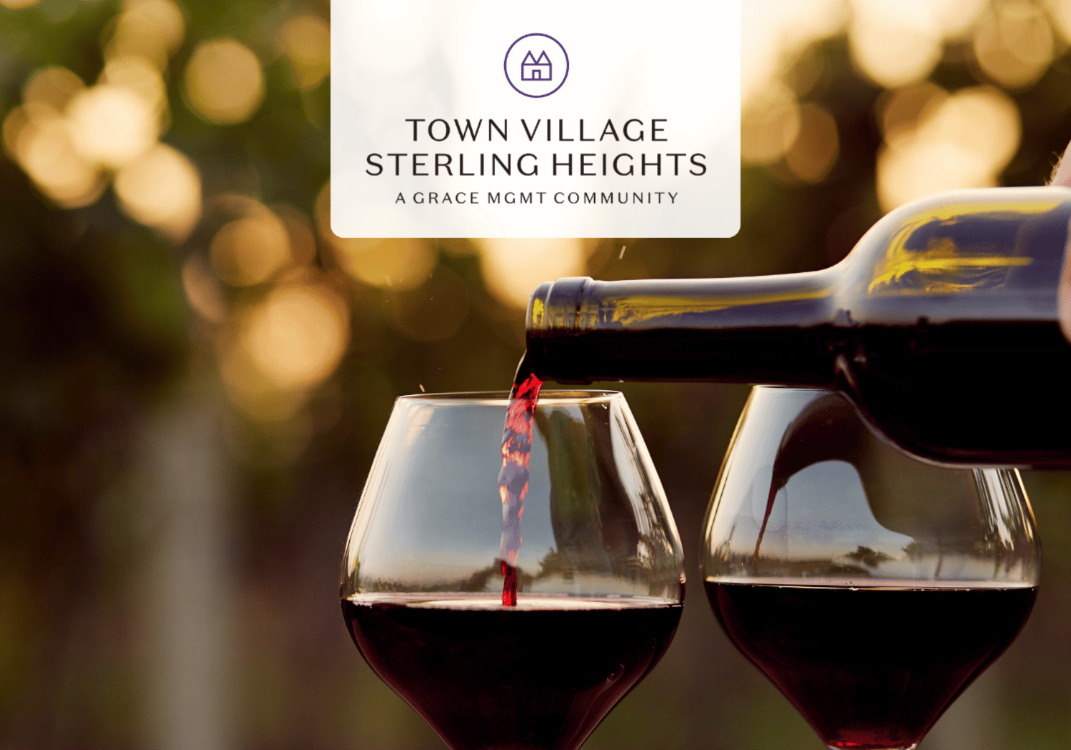 Wine being poured from a bottle into two red wine glasses outdoors, with a blurred golden background and a Town Village Sterling Heights logo above.